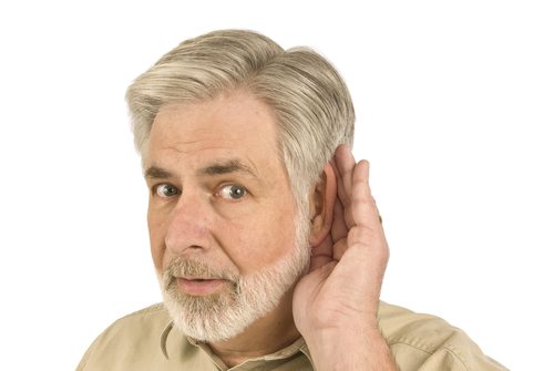 An older man cupping his hand around his ear to hear better