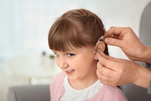 child with hearing loss being fitted for hearing aid