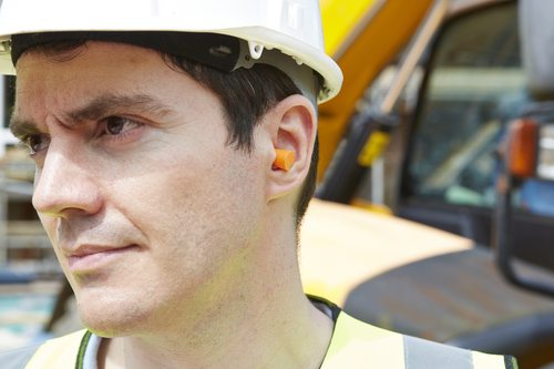 A worker on a noisy construction site wearing hearing protection.