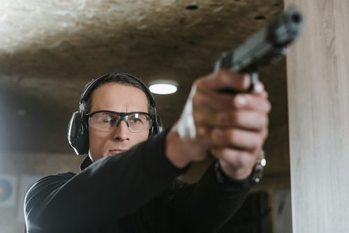 A man practicing shooting with hearing protection on his ears