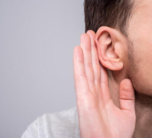 A man cupping his hand around his ear to hear better.